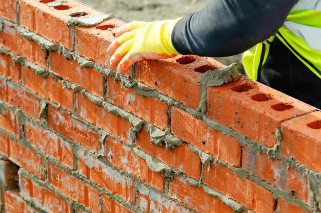 bricklayer-laying-bricks-mortar-new-residential-house-construction_245726-1838