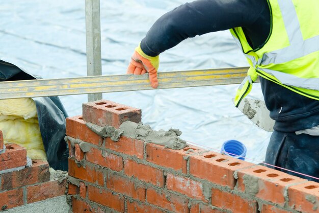 bricklayer-laying-bricks-mortar-new-residential-house-construction_245726-1952