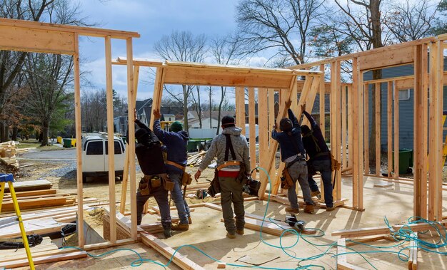 construction-worker-using-nail-gun-wood-building-frame-against-house-build_73110-17977