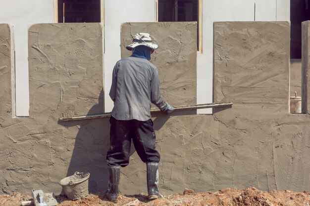 construction-workers-plastering-building-wall-using-cement-plaster_9635-2920