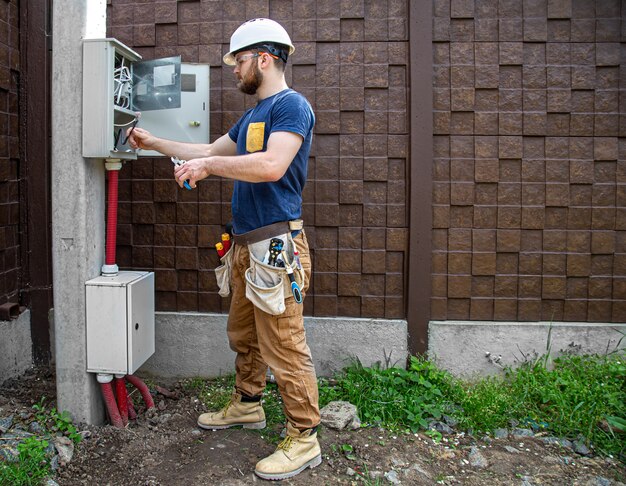 electrician-builder-work-examines-cable-connection-electrical-line-fuselage-industrial-switchboard-professional-overalls-with-electrician-s-tool_169016-7334