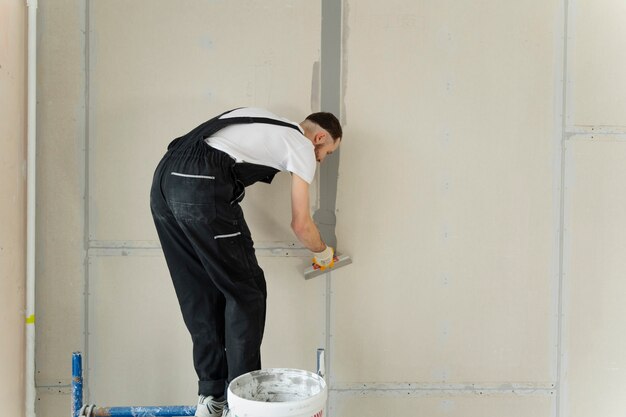 full-shot-construction-worker-using-plastering-trowel_23-2149328074