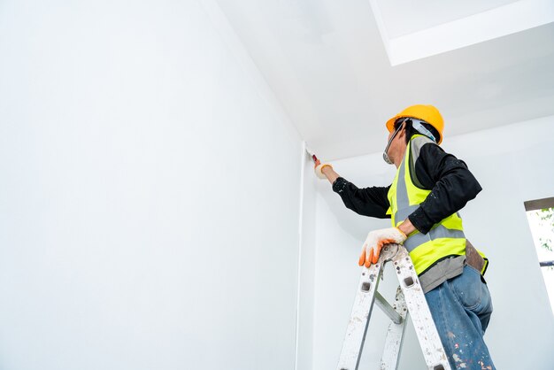 painter-man-painting-wall-unfinished-building-with-paint-brush-isolated-big-empty-space-with-wooden-ladder-construction-site_61243-1123