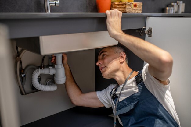 plumber-repair-experienced-attentive-middleaged-man-examining-bottom-kitchen-sink_259150-58266